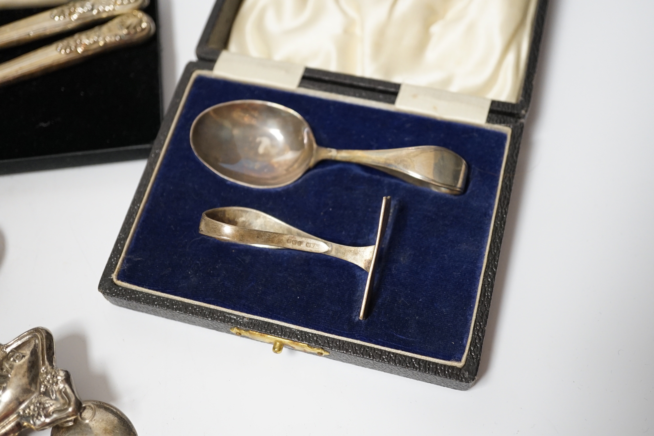 A cased silver christening spoon & pusher, a Georgian silver christening knife and fork, six silver bean end coffee spoons, a child's silver rattle, silver sugar tongs and a silver mounted photograph frame, Birmingham, 1